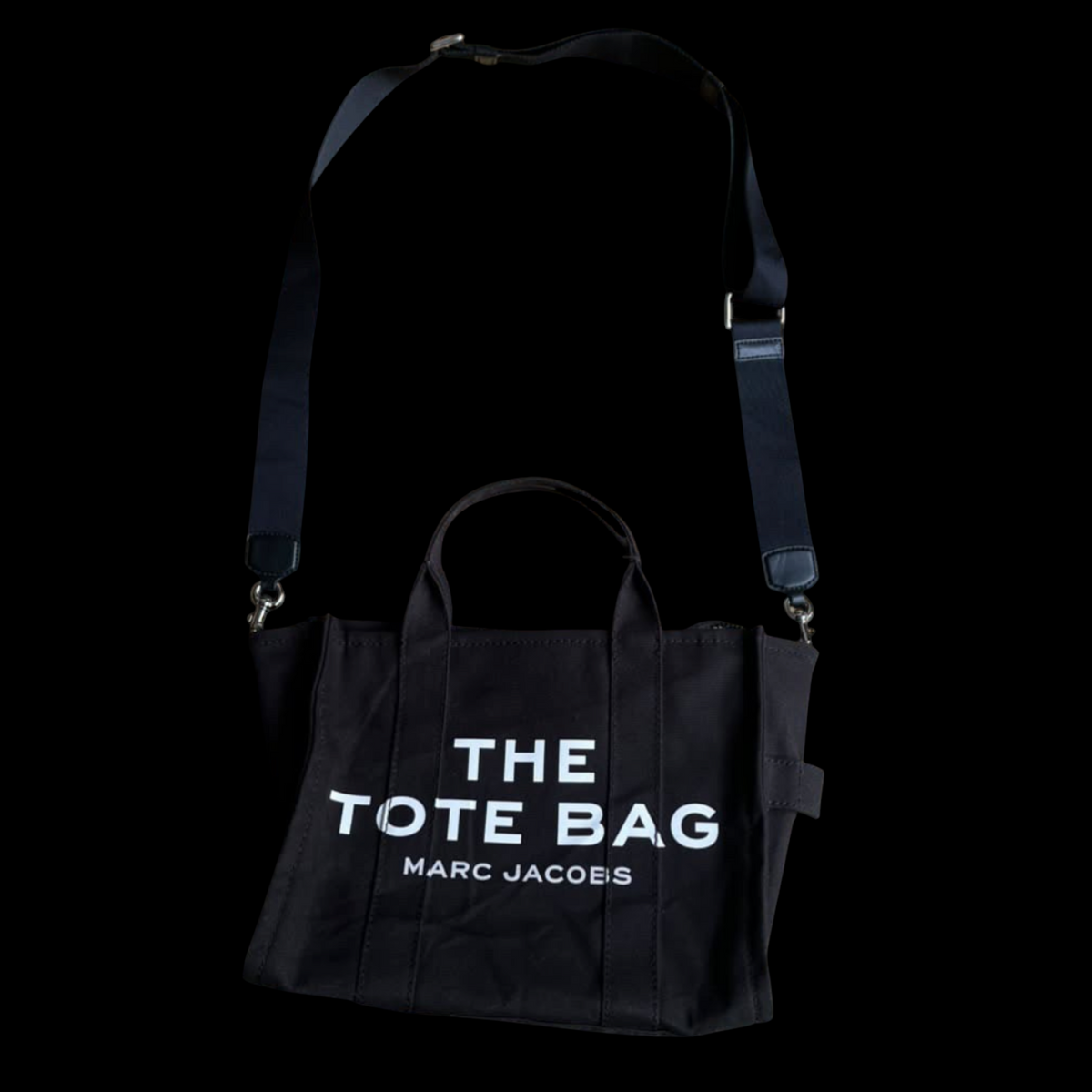 Bolsa Marc Jacobs The Tote Bag preta em lona com alça tiracolo ajustável, disponível no garimpo do madruga