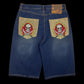 Bermuda jeans azul garimpo do madruga com bordados de caveira e espadas nos bolsos traseiros