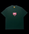 Camisa verde-escura da garimpo do madruga com estampa geométrica rosa e preta no peito. Gola redonda, manga curta.