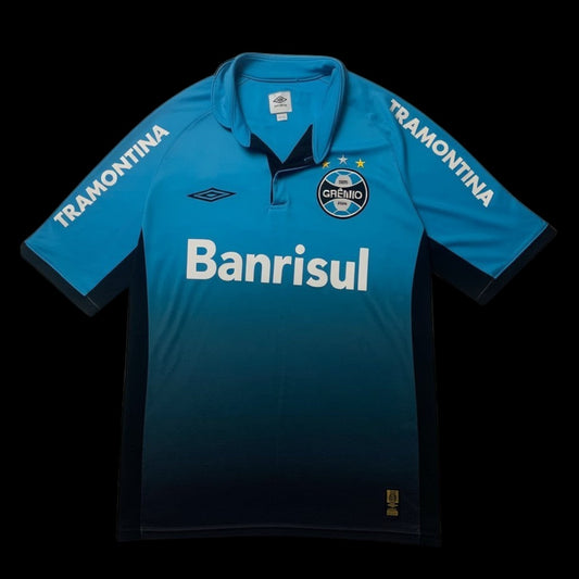 Camisa de futebol Umbro X Grêmio 2015 azul e preta com logo do time e patrocinador Banrisul. Detalhe de listras "Tramontina" nas mangas.