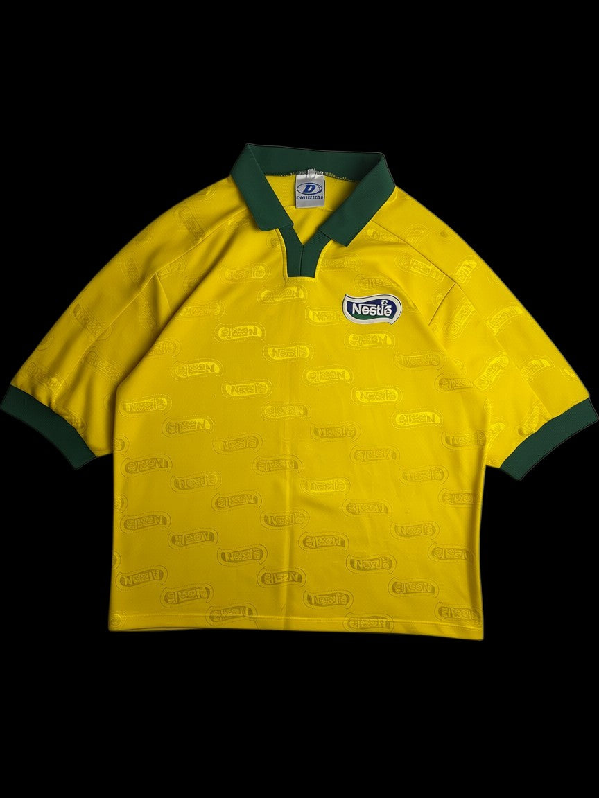 Camisa amarela vintage Dellerba x Nestlé dos anos 90 com gola e punhos verdes. Logo Nestlé em relevo por toda a peça.