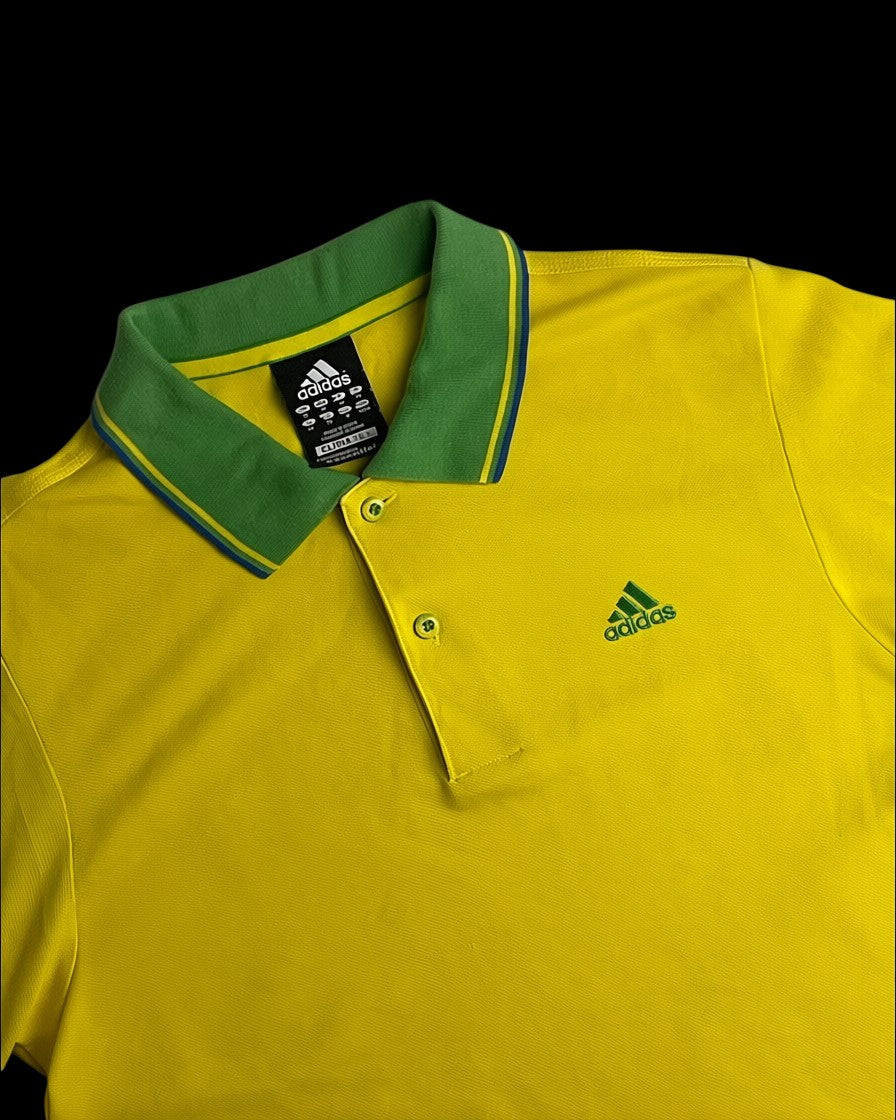 Camisa polo amarela da Adidas com gola verde e detalhes azuis. Logo Adidas bordado no peito.