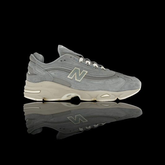 Tênis New Balance 1000 Kith 101 cinza em camurça e mesh, com solado bege e detalhes futuristas.
