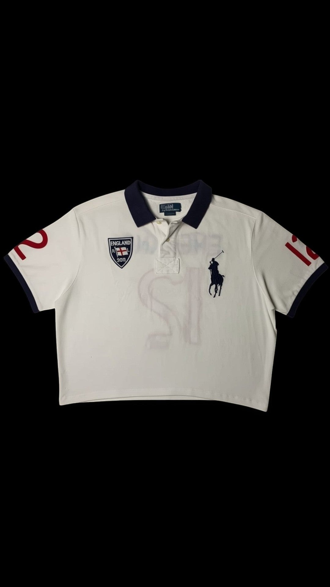 Polo cropped branco da garimpo do madruga com gola azul marinho, logo do cavalo e jogador de polo bordado, escudo da Inglaterra e número 12 nas mangas. Peça de upcycling.